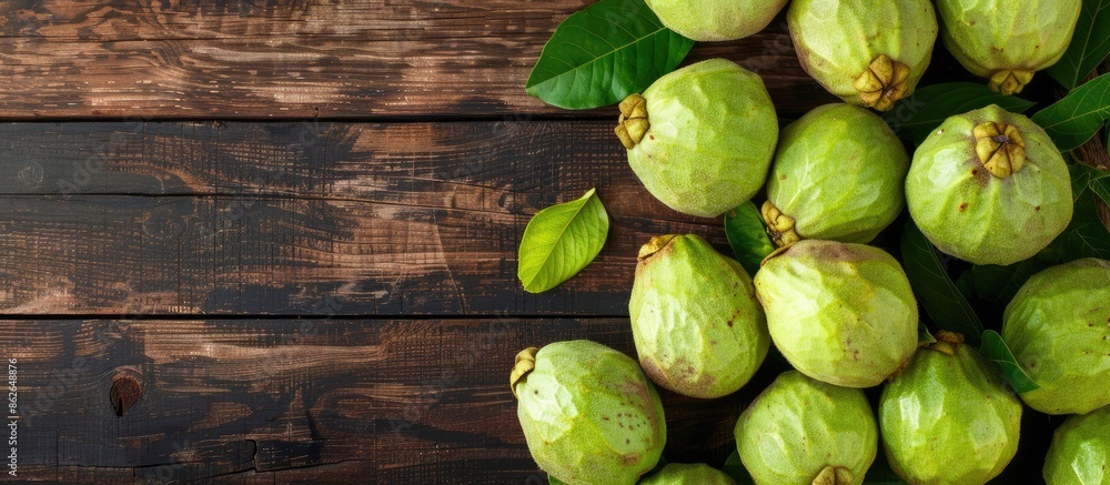 Poster Top view of ripe green guavas displayed on a rustic wooden surface with copy space image.