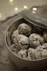 delicious chocolate gingerbread cookies in powdered sugar. festive tin box. gift for new year christmas. cozy lights and textiles on the background
