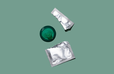 Condom out of package on a mint green background. A condom use to reduce the probability of...