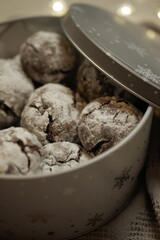 delicious chocolate gingerbread cookies in powdered sugar. festive tin box. gift for new year christmas. cozy lights and textiles on the background
