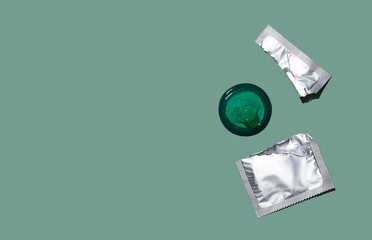 Condom out of package on a mint green background. A condom use to reduce the probability of pregnancy or sexually transmitted disease (STD). Safe sex and reproductive health concept. Top view.