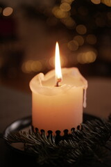 Christmas and New Year cozy  atmosphere. white candle in a black candlestick is burning against the background of blurry Christmas tree garlands. candle flame

