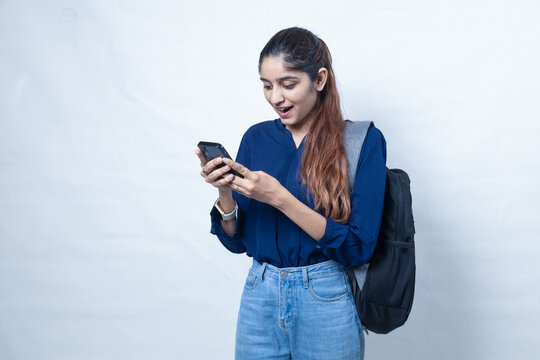 Indian school girl checking exam result in smart phone. education and learning concept. Isolated over grey background.