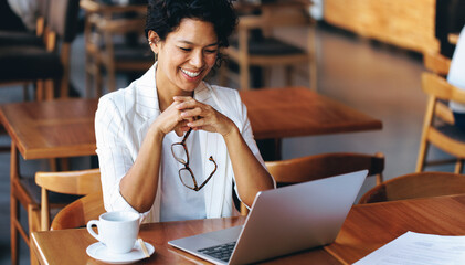 Happy businesswoman working on laptop in a cafe, enjoying coffee and feeling productive