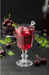 Fresh cherry cocktail. Fresh summer cocktail with cherries, mint and ice cubes. Glass of cherry soda drink on a black background.