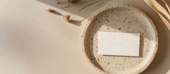 Handmade paper with a raw edge displayed on a terrazzo plate against a beige backdrop for a branding concept, featuring a name card mock-up with copy space image.