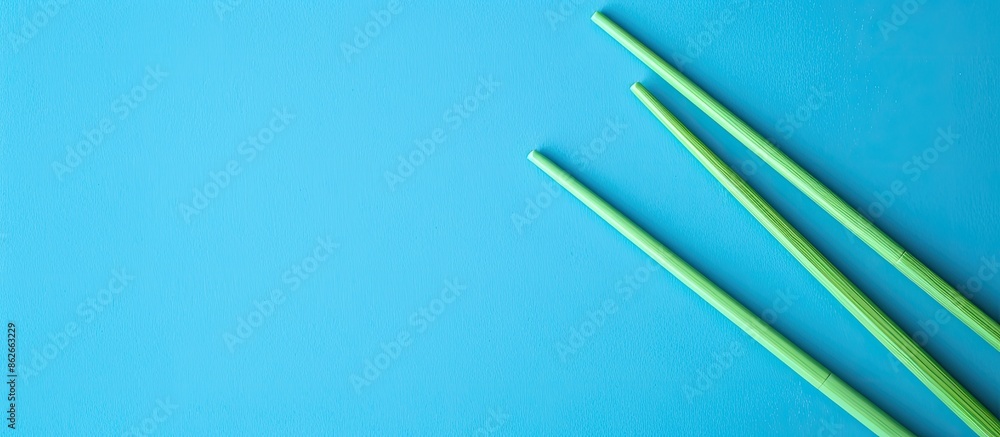 Poster green wooden chopsticks on a blue background in a top-down view with copy space image.