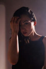 Stylish asian woman with wet hair looking at camera on grey background