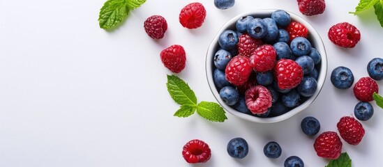 Cookie cutter filled with blueberries and raspberries on a white background with mint leaves nearby - fresh berries in a cookie form copy space image.