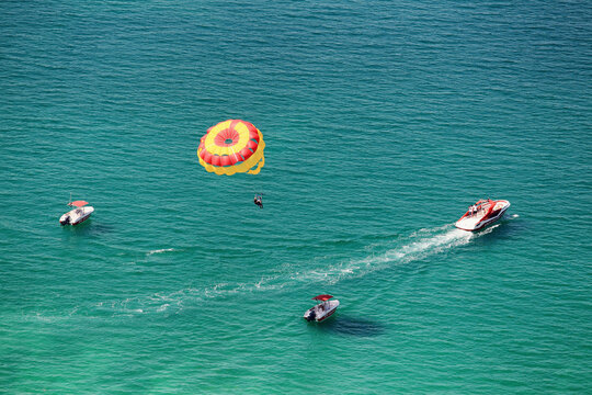 View of parasailing over ocean with motorboats and people, Dubai, United Arab Emirates.