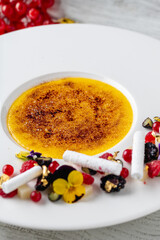 Creme brulee on white porcelain plate on wooden table