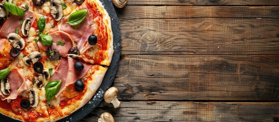 Top view of a slate platter showcasing a half pizza topped with ham, mozzarella, mushrooms, and olives on a wooden background with copy space image.