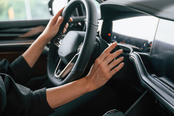 Focused close up view of woman hands that are driving new car