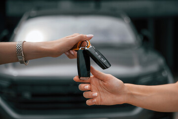 Order is finished. Woman hands are giving and taking the keys for the new automobile