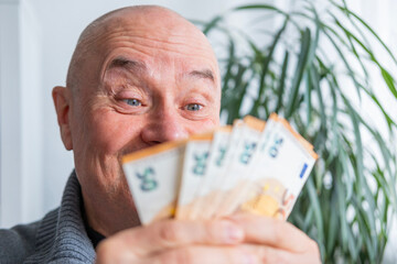 satisfied man holding euros, euro money in fan, rejoices in success, anticipates what to spend it...