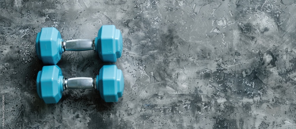 Poster cyan blue plastic dumbbells on a grey textured background for a fitness concept, with a pair of smal