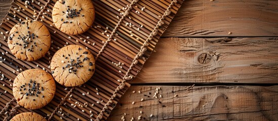 Naklejka premium Top view of delicious walnut cookies on a sushi mat sprinkled with black sesame seeds, creating an appealing dessert display with space for text or images. Copy space image