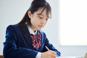 学校の教室で授業を受ける冬の制服を着た女子高校生