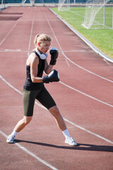 Fototapeta premium young female boxer training in the stadium, standing in position