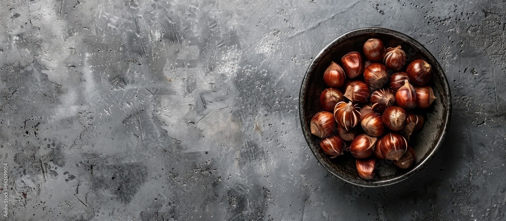 Poster on a gray rustic table lies a pile of roasted sweet chestnuts. plenty of space around for a copy spa