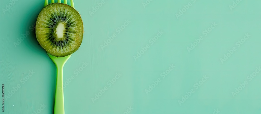 Poster Minimal style concept with a kiwi on a green plastic fork displayed against a pastel green background, creating a fresh, summery vibe with copy space image.