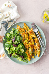 Fried zucchini flowers in batter and mix salad with cucumbers, top view