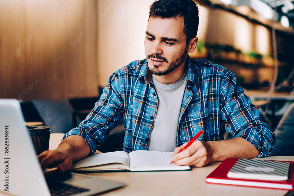 Poster male student browse information for studying language via online courses on netbook in coworking off