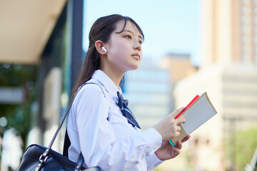 バス停にて参考書で勉強をする女子高校生