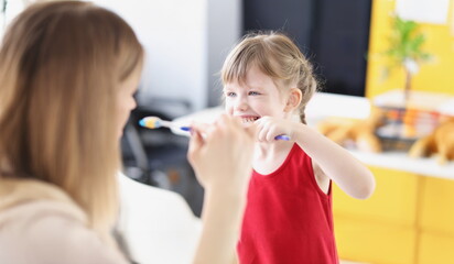 Dentist shows girl how to brush her teeth properly. Oral hygiene in preschool children concept