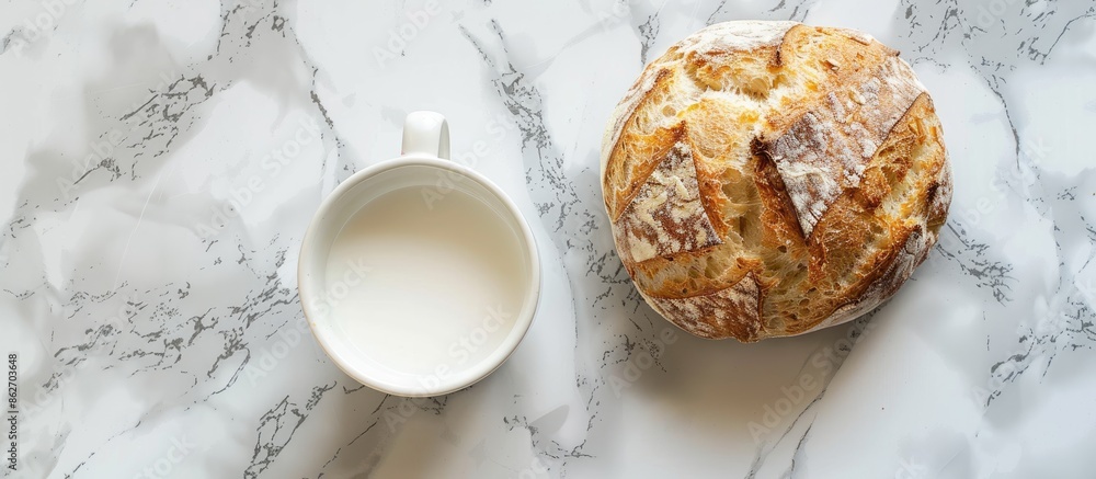 Poster top view image showcasing a white round bread placed alongside a mug of milk on a marble surface, wi
