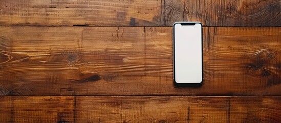 Top view of a smartphone on a teak wooden table with white screen for copy space image.