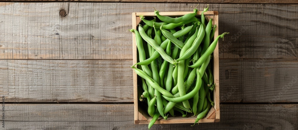 Poster fresh organic green common beans or kidney beans in a wooden box for cooking, set against a wooden b