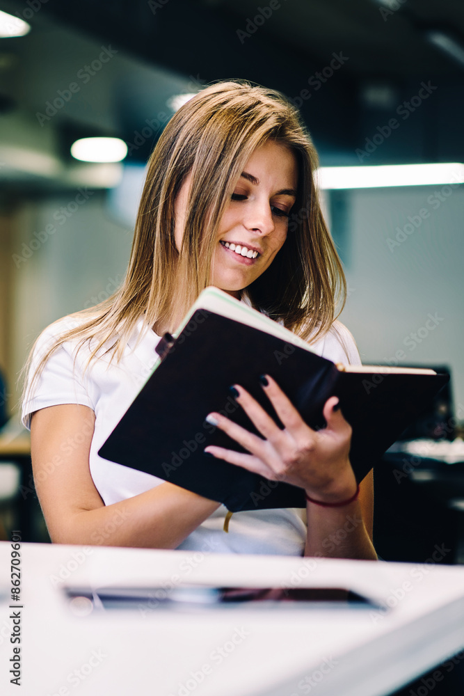 Poster smiling hipster girl holding notepad checking items in to do list satisfied with completing tasks in