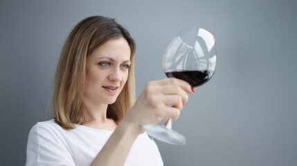 Young woman looking into glass with red wine. Wine tasting concept