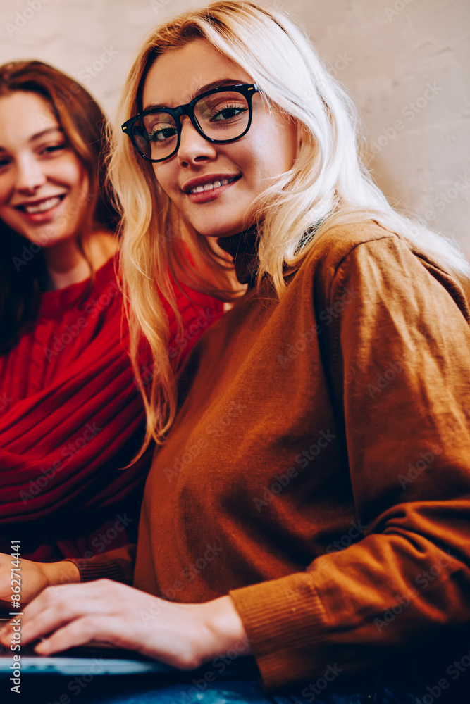 Poster portrait of hipster girl browsing on netbook resting on break with best friend, positive female teen