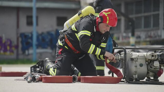 A special team of firefighters seizes hoses from a firetruck and embarks on a perilous mission to extinguish a blazing fire, showcasing their bravery and professional expertise in tackling a hazardous
