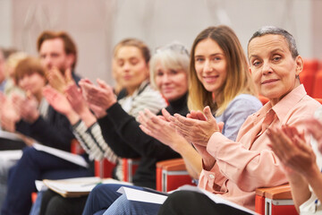 Smiling professionals applauding at business event in auditorium