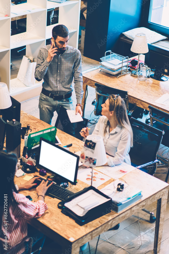 Poster young man leader of company calling on smartphone while talking with employee during busy working pr