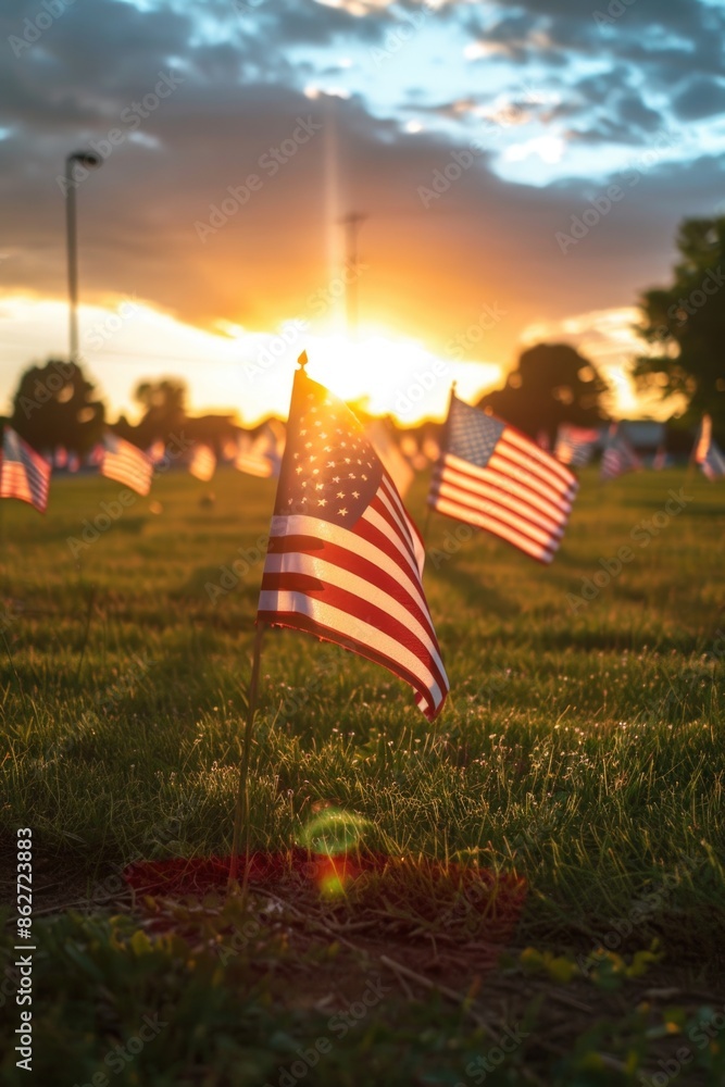 Poster a field of american flags are lined up in a row. the sun is setting in the background, casting a war