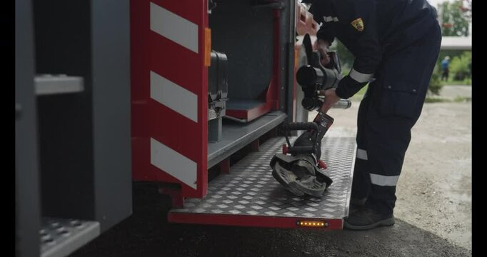 A professional firefighter meticulously prepares dangerous metal-cutting equipment on a firetruck, showcasing their readiness and expertise for high-stakes rescue operations in emergency situations