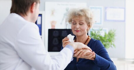 Doctor compassionately supports elderly woman at medical appointment. Advanced disease in old age concept