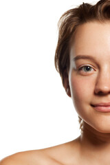 Fototapeta premium close-up of a woman's face, focusing on one eye and half her smile, highlighting her clear skin and natural beauty. Concept of youth, beauty and fashion, cosmetic product, dermatology. Ad
