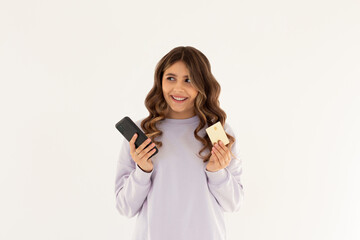 Online shopping. Smiling good-looking woman paying for order, using plastic credit card to pay with mobile phone, standing against white background