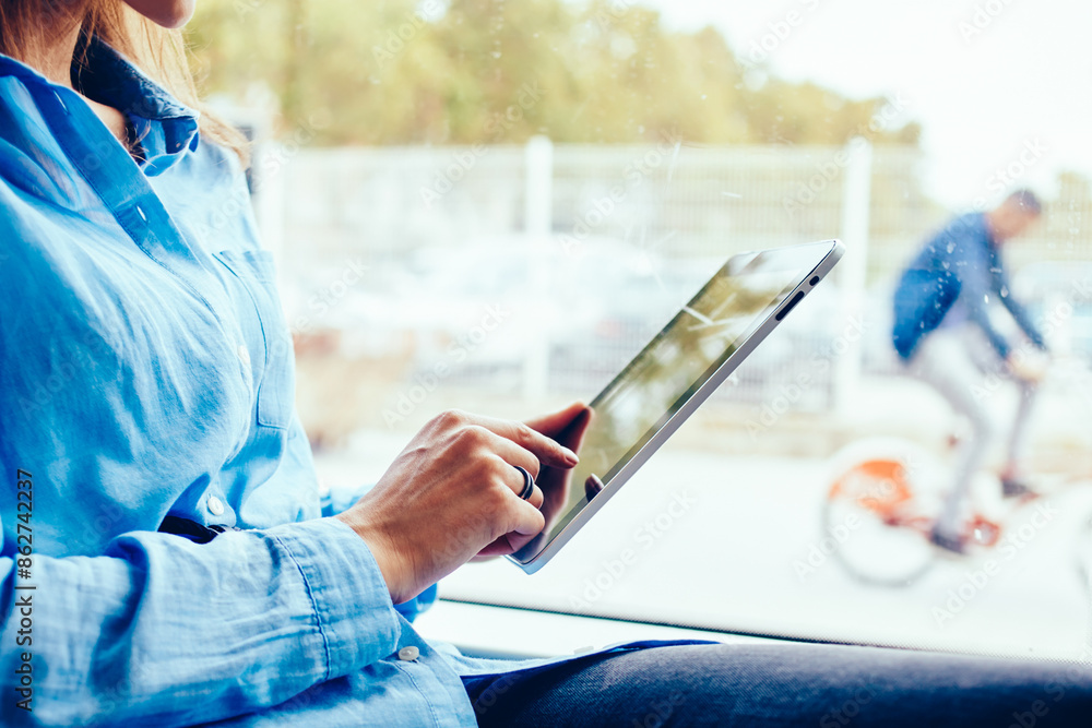Poster cropped side view of hipster girl touching with finger on display of modern touch pad using public t