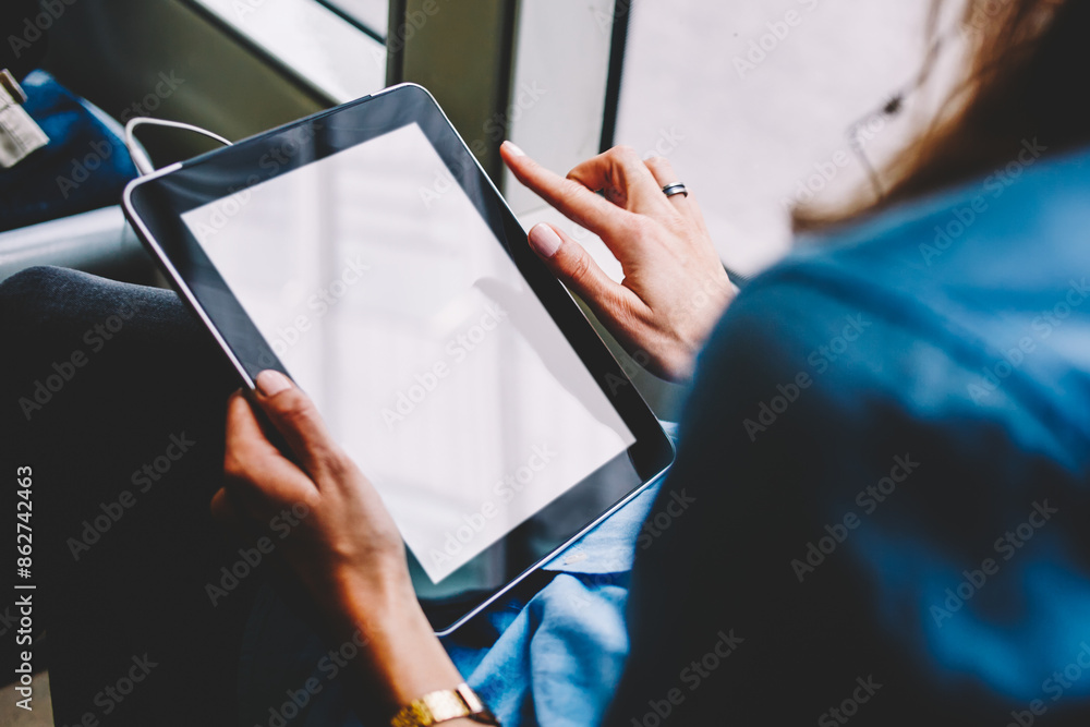 Poster cropped back view of female person holding modern touch pad device with copy space display for your 