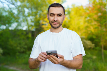 Happy young handsome man using phone at the park