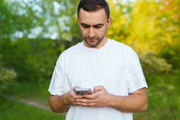 Fototapeta premium Picture of bearded man, browsing the internet on his phone enjoying a lovely day outside.