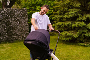 Happy father with child in stroller walking at summer park