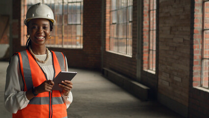 Confident Female Engineer in Safety Gear Holding Tablet in a Construction Site