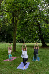 Beautiful women doing yoga stretching their bodies in nature. Healthy lifestyle.  Vertical photo 